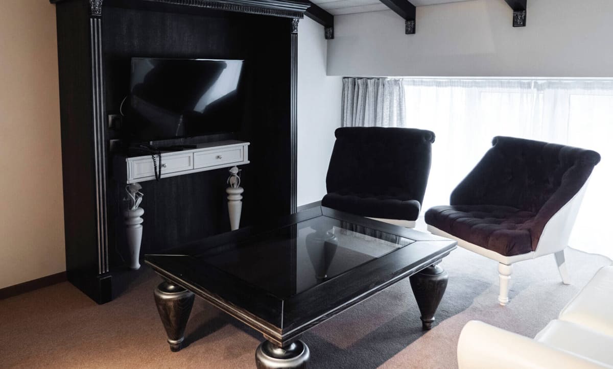 Cozy reading nook with an armchair and wooden side table in a hotel room - yavorina.com.ua